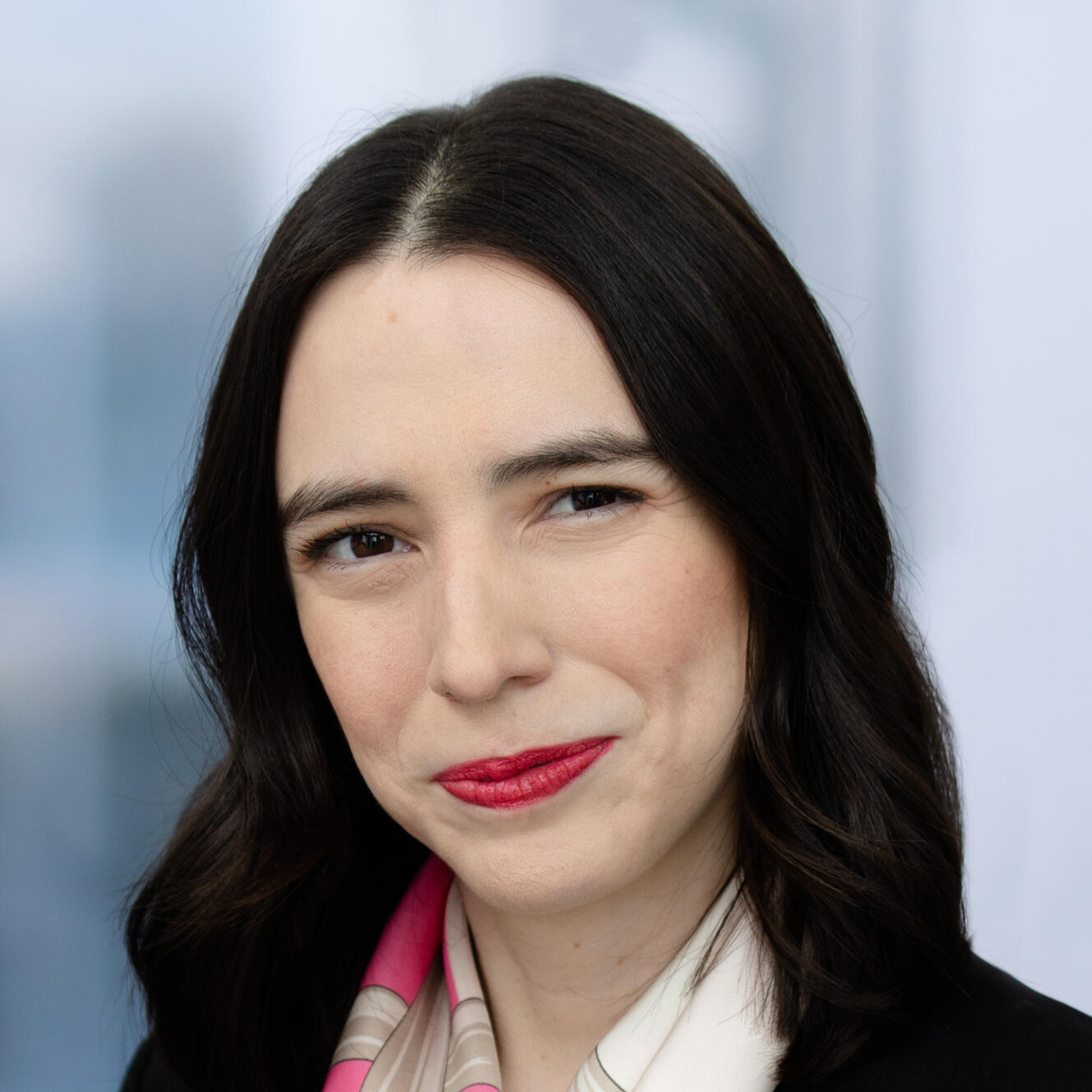 Image of me (Delle), a light-skinned Hispanic woman with brown eyes and very dark brown hair, currently wearing a black sport coat, with a white-and-pink silk scarf tied around my neck like a tie